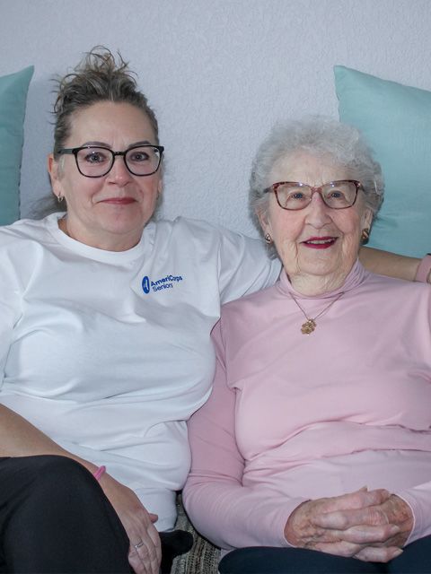 Two smiling women, one much older than the other, pose for the camera with their faces close together. They look very happy. 